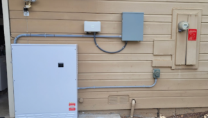 A picture of a power source on the side of a newly built house, an example of a structure that could greatly benefit from solar power for new home construction.